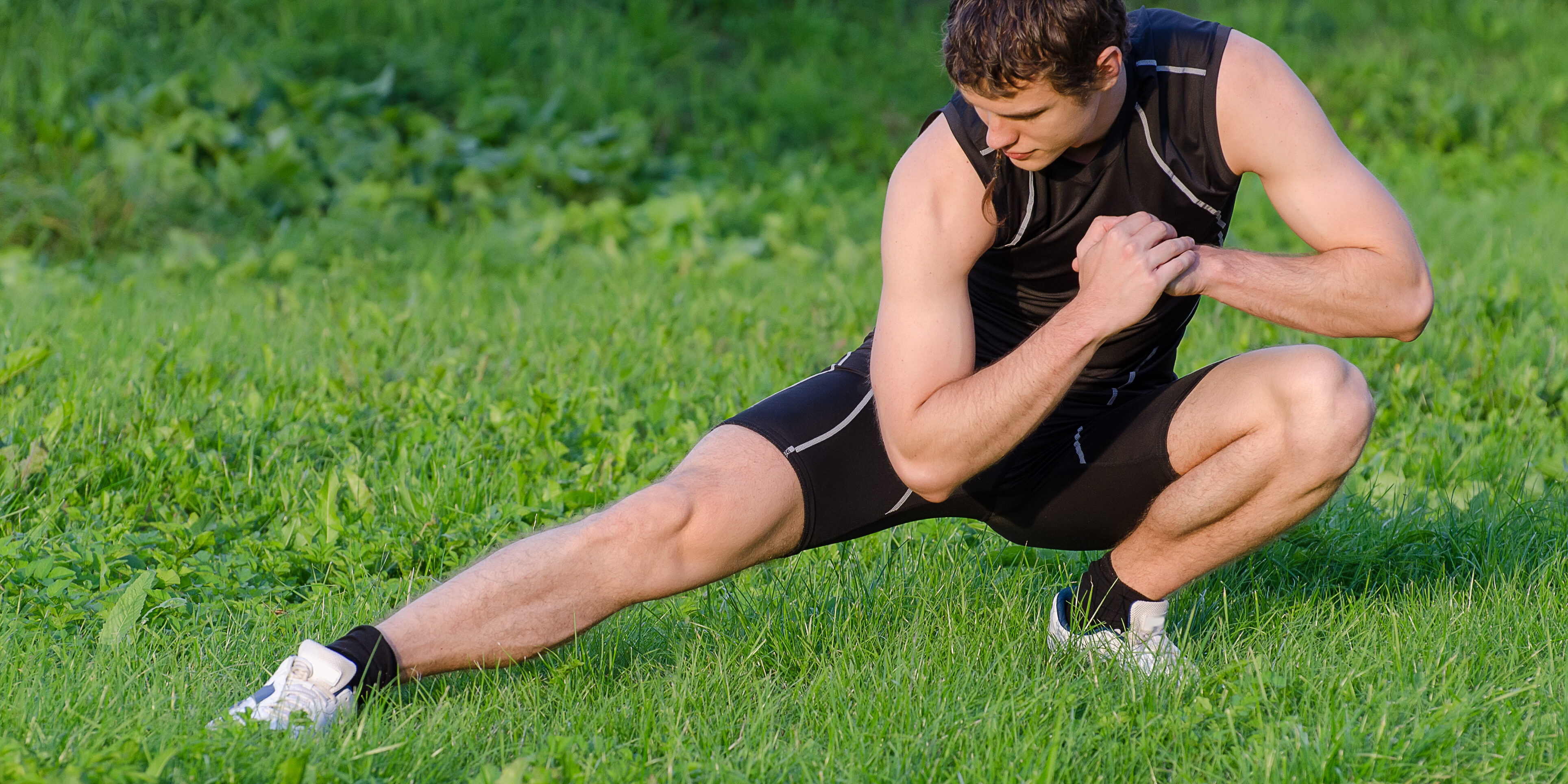 Young sportsman warming up before workout in park